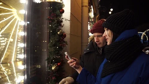 Young happy couple using smartphone on a busy urban street in evening Stock Footage 83873745