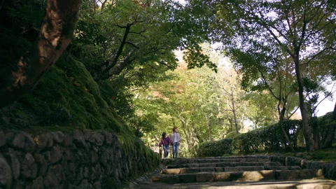 Young happy couple walking down stone steps in a shaded forest in Kyoto, Japan w Stock Footage 199458706