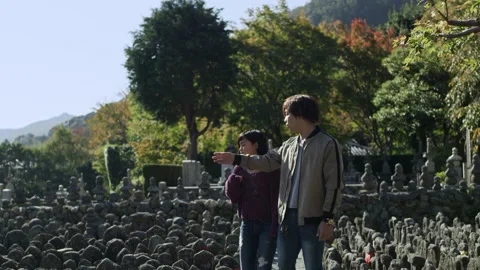 Young happy couple walking through a Buddhist shrine and looking at the stone st Stock Footage 199457758