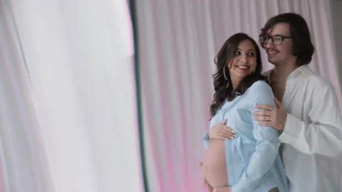 Young happy family expecting baby hug and smile at photo shoot in studio Stock Footage 169793953