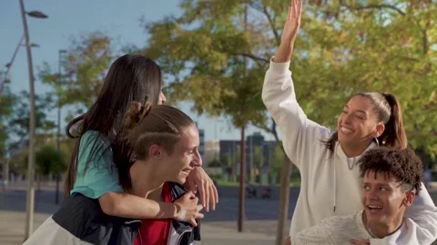 Young happy friends playing down the street hitting high five. 스톡 동영상 164777928