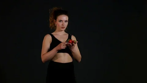 Young happy girl with fresh strawberries on black background Stock Footage