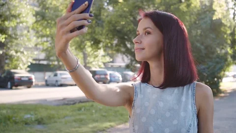 Young happy girl is taking photo outdoors. Stock Footage