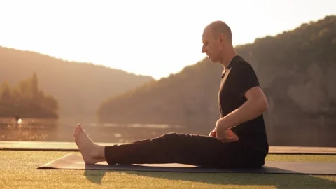 Young happy guy doing yoga outdoors in the morning on the river bank. Stock Footage 246559434