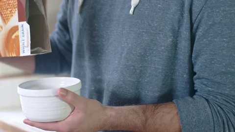 Young happy hispanic man pouring cereal into white bowl Stock Footage 84456595