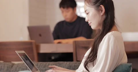 Young happy Japanese couple using smart devices at home remote work working from Stock Footage 147570254