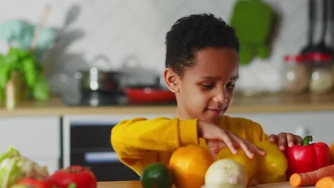 Young happy kid sorting fresh fruits and vegetables on kitchen table helping Video stock 147270819