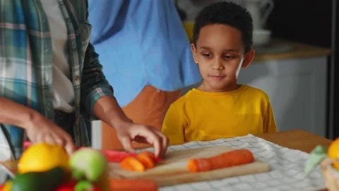 Young happy kid talking with mom cooking lunch together cutting vegetables at Stock Footage 147270964