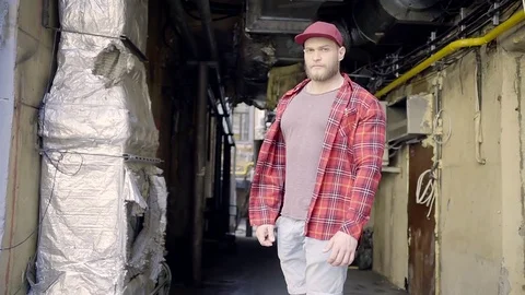 Young happy man with a beard in comfortable working clothes stands in the yard Stock Footage 76861064