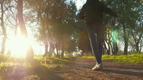 Young happy man dancing and walking in the beautiful park on sunset. Green grass Stockbeeldmateriaal 106731506