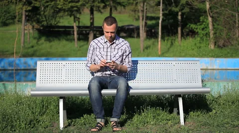 Young happy man relaxing on bench in city park Stock Footage 33953683
