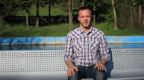 Young happy man relaxing on bench in city park Stock Footage 33953839