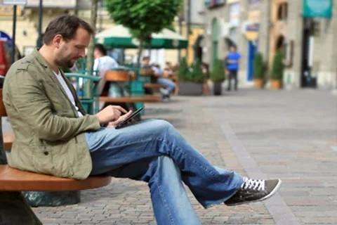 Young happy man with tablet computer sitting in the city NTSC Stock Footage 8524066