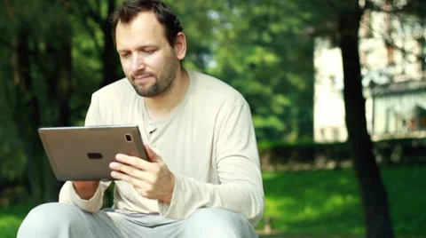 Young happy man with tablet computer in the park Stock Footage 8579764