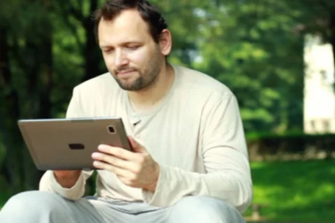 Young happy man with tablet computer in the park Stock Footage 8579952