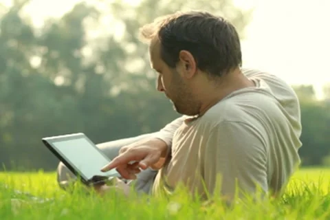 Young happy man with tablet computer lying on the grass Stock Footage 8580750