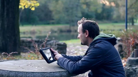 Young happy man with tablet computer sitting in the park HD 스톡 동영상 8917925