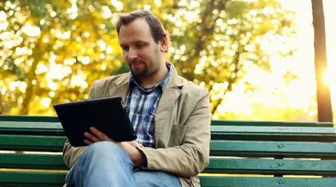 Young happy man with tablet computer sitting in the park Stock Footage 8950862