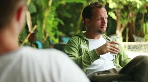 Young happy man talking and drinking beer in bar, outdoors Stockbeeldmateriaal 10786531