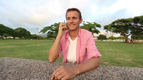 Young Happy Man Talking On Mobile Phone In The Park Stock Footage 55627188