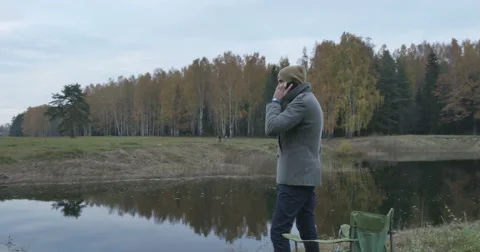 Young happy man talking on mobile phone in the park Stock Footage 63364495