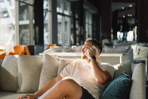 Young happy man using mobile phone in hotel lobby. Foto stock