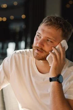 Young happy man using mobile phone in hotel lobby. Stock Photos