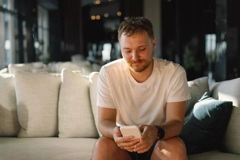 Young happy man using mobile phone in hotel lobby. Foto stock