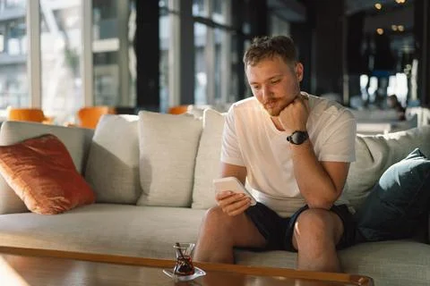 Young happy man using mobile phone in hotel lobby. Stock Photos