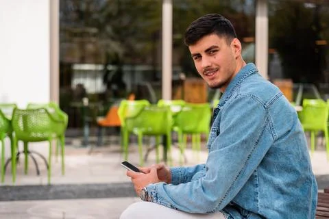 A young happy man using a phone in the cafe. Stock Photos