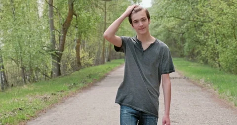 Young happy man is walking alone on the road. Cheerful teenager walks through Stock Footage 142565405