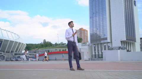 Young happy man walking down the street White shirt, black tie. phone at hand Stock Footage 91492989