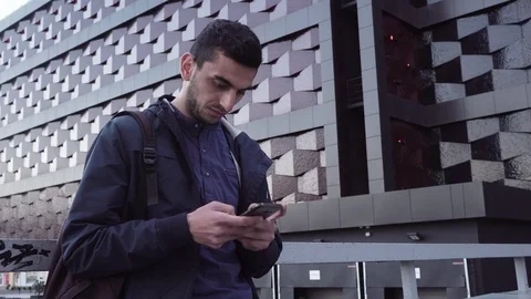 Young happy middle eastern man using a smartphone and smiling in city Stock Footage 88773747