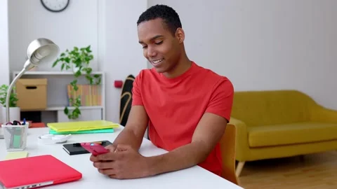 Young happy millennial boy using mobile phone sitting on desk at home Stock Footage 271296172