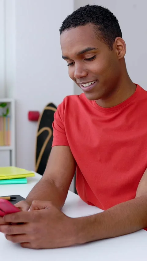 Young happy millennial boy using mobile phone sitting on desk at home Stock Footage 274498954