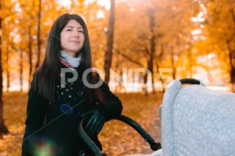 Young happy mom with a stroller in autumn park Stock Photos