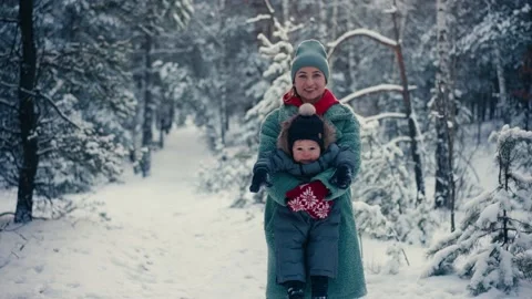 Young happy mother having fun and playing with toddler son in snowy forest in Vidéo 167954319