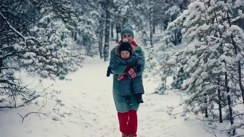 Young happy mother having fun and playing with toddler son in snowy forest in Video stock 167954497
