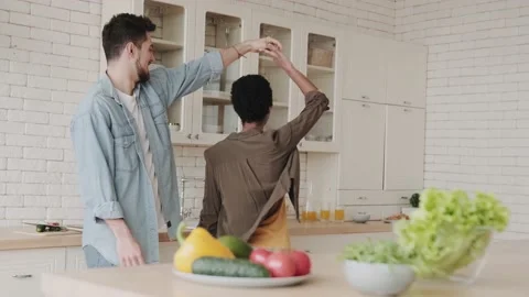 Young happy mutinous couple dancing in the kitchen near the table with Stock Footage 238021138