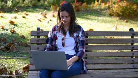 Young happy smiling girl using computer in park Stock Footage 101572306