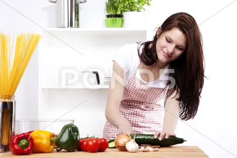 Young happy woman cutting cucumber Stock Photos