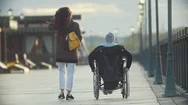 Young Happy Woman With Disabled Man In A Wheelchair Walking Together On The Quay Stock Footage