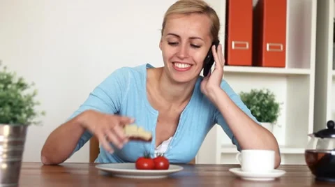 Young happy woman having breakfast while talking on cellphone, dolly shot Stock Footage