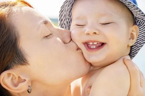 Young happy woman kisses her adorable cheerful baby Stock Photos