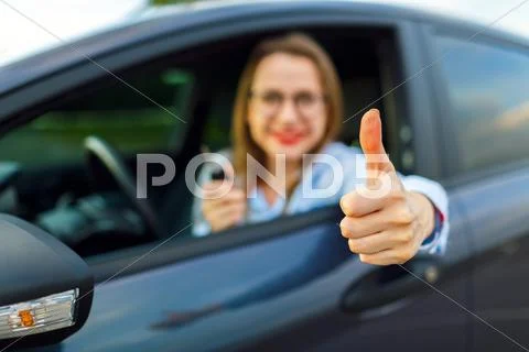 Young happy woman sitting in a car with thumb up Stock Photos