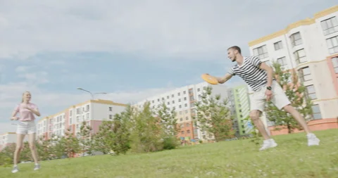 Young having fun with a disc on a summer meadow. Tracking shot of young men and Stock Footage 141128279
