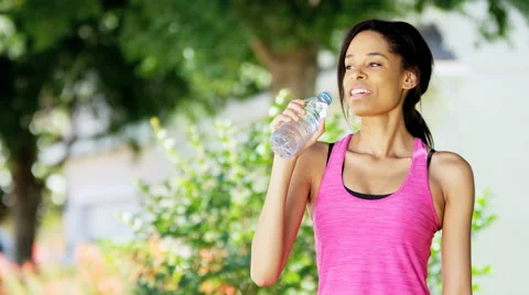 Teenage girl drinks water from bottle Stock Photo by