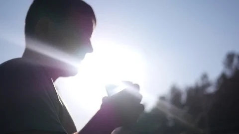 A young healthy man drinks clean water from a glass goblet, standing against the Stock Footage 75453461