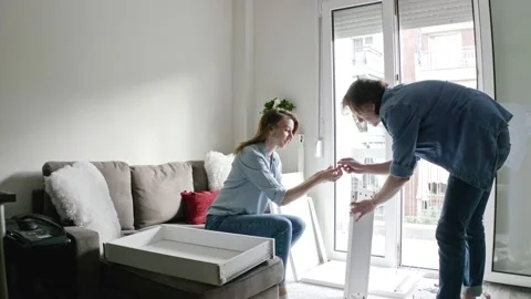 Young heterosexual couple assembling together DIY furniture at home. Video stock 132587232