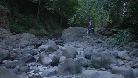 Young Hiker with backpack and camera takes in and appreciates riverbed Stock Footage 141798438